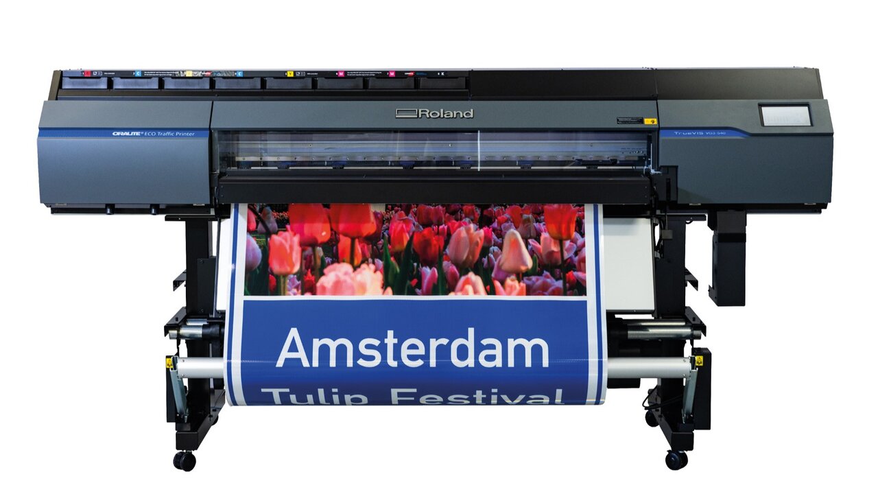Front view of the Roland ORALITE® ECO Traffic Printer, which is used to print standard traffic signs with a long service life. The printer unrolls a sign with a bright red tulip field and the words "Amsterdam Tulip Festival".