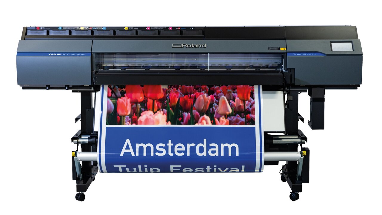 Front view of the Roland ORALITE® ECO Traffic Printer, which is used to print standard traffic signs with a long service life. The printer unrolls a sign with a bright red tulip field and the words "Amsterdam Tulip Festival".