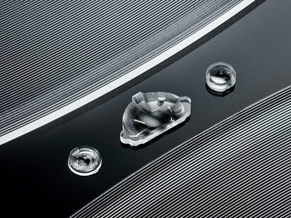 Fresnel-Linsen aus Kunststoff in sehr unterschiedlichen Dimensionen, eine wenige Millimeter große Fresnel-Linse zwischen zwei Linsen mit mehreren hundert Millimetern Durchmesser